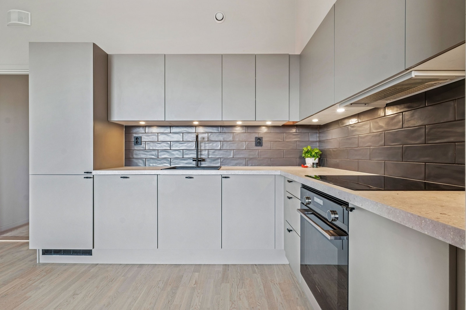 Kjøkken med integrerte hvitevarer, rikelig oppbevaring og sorte detaljer. Galleribilde