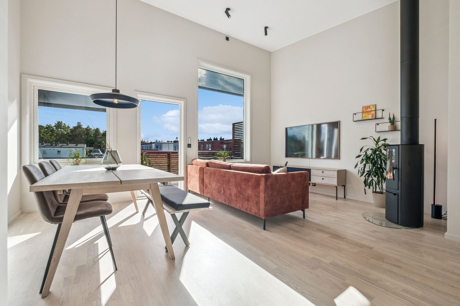 Lys og romslig stue med opptil fire meter takhøyde og store vinduer – sorte detaljer gir et eksklusivt preg. Galleribilde