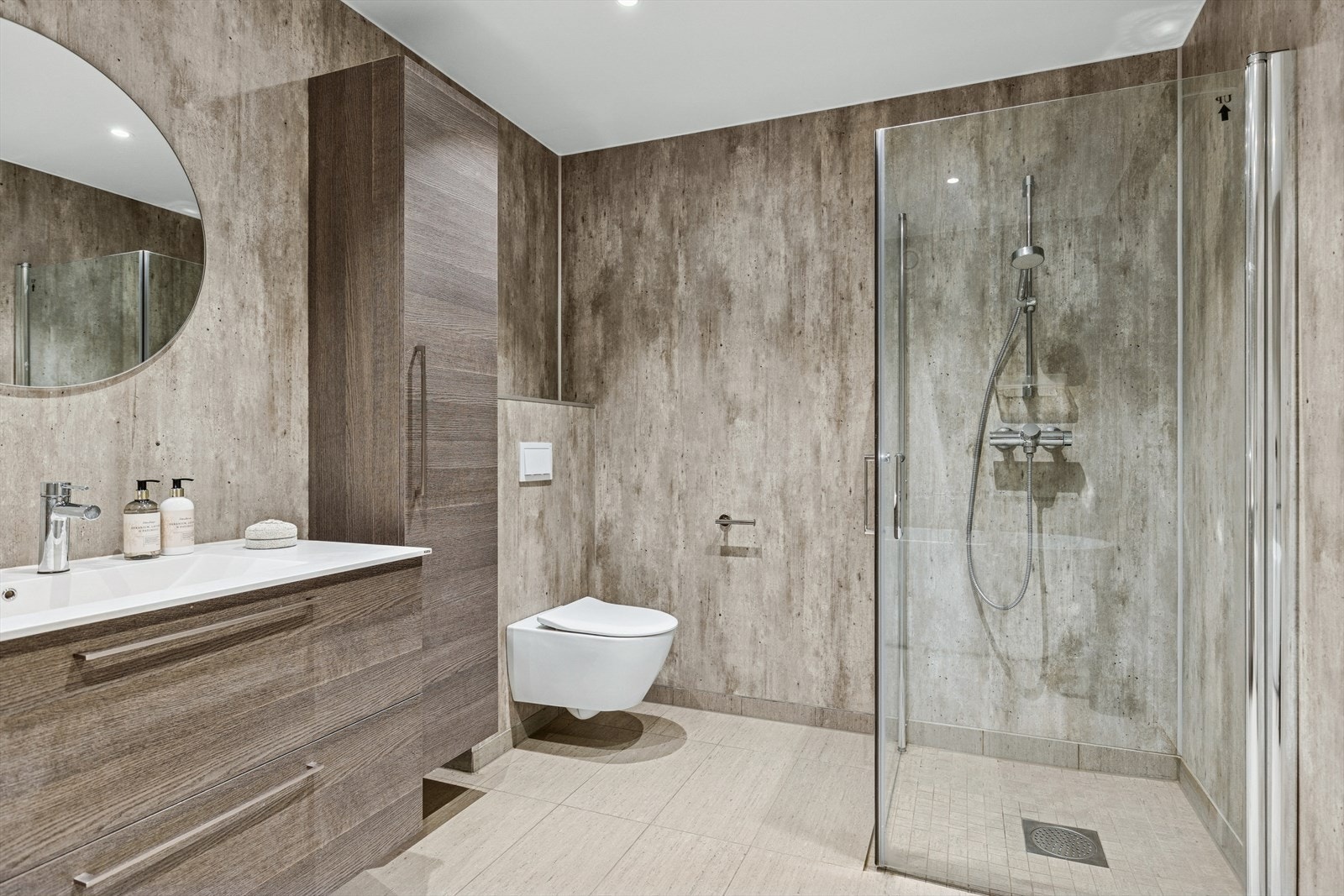 Innbydende bad med fliser på gulv. Våtromsplater på vegg. Rommet har dusjhjørne, badekar, seksjon med heldekkende vask og veggmontert toalett. Galleribilde