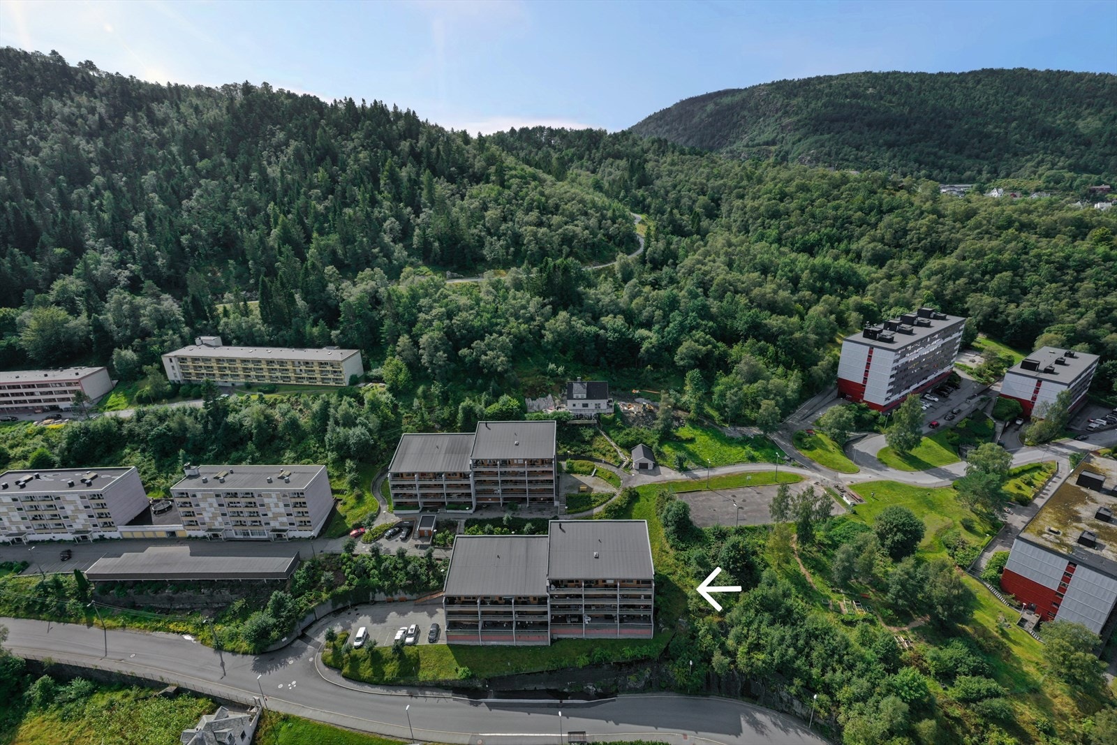 Legg merke til Løvstien som går like over borettslaget. Busstoppet ligger like nedenfor boligen. Det er garasje i byggets 1.etasje, samt gjesteparkering rett utenfor. Galleribilde