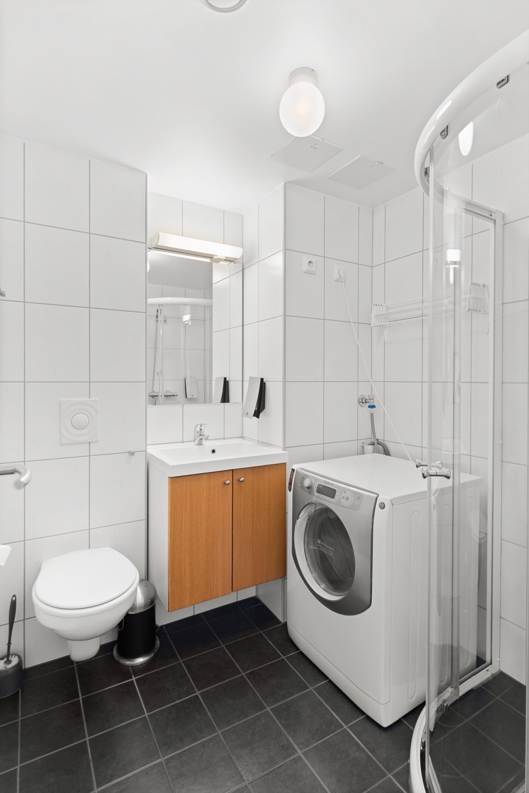 Badet er innredet med toalett, dusj på gulv og servant Galleribilde