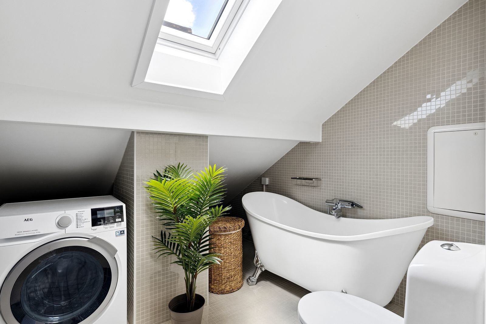 Pent, flislagt bad fra 2016, innredet med badekar, servant med underskap, speil og toalett. Galleribilde