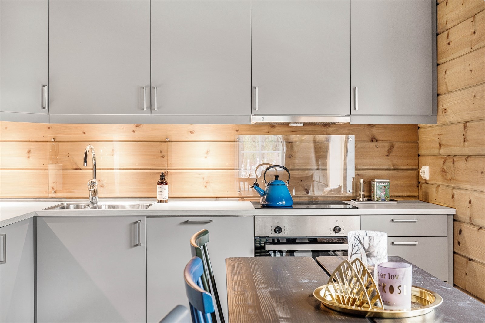 Østerdalspanel i pen kontrast mot tidløs grå. Et kjøkken som står seg i tiden, og hvor du enkelt kan tilføre eget interiør. Godt med skapplass og tidløs utførelse i rolig grå. Galleribilde