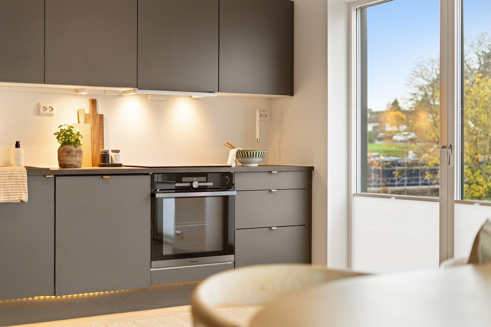 Lekkert kjøkken med god belysning og stilrene overflater. Store vinduer gir rikelig med naturlig lys og utsikt. Galleribilde