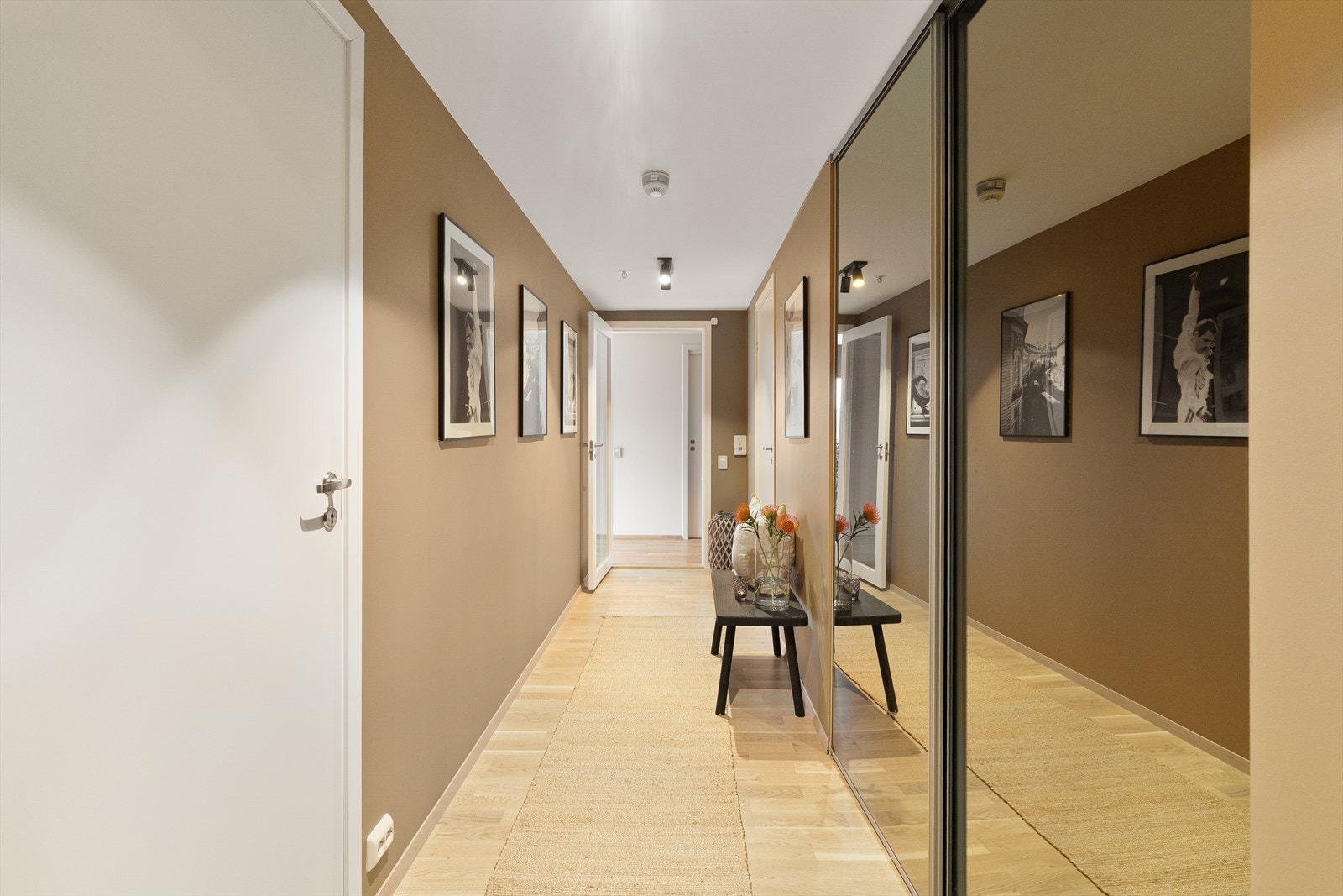 Elegant gang med innfelt garderobe løsning og kunst på veggene, som gir en romslig og stilfull velkomst til boligen. Galleribilde