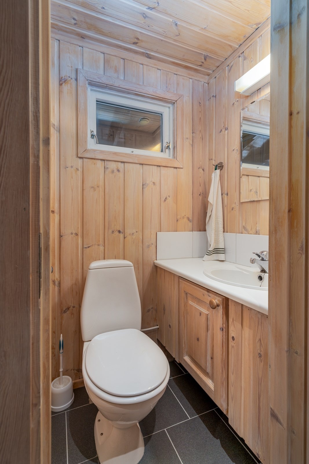 Hytta har to toaletter. Her fra det praktiske toalettrommet med flislagt gulv og termostatstyrt gulvvarme. Rommet er innredet med servantskap, speil med overlys, servant og wc. Galleribilde