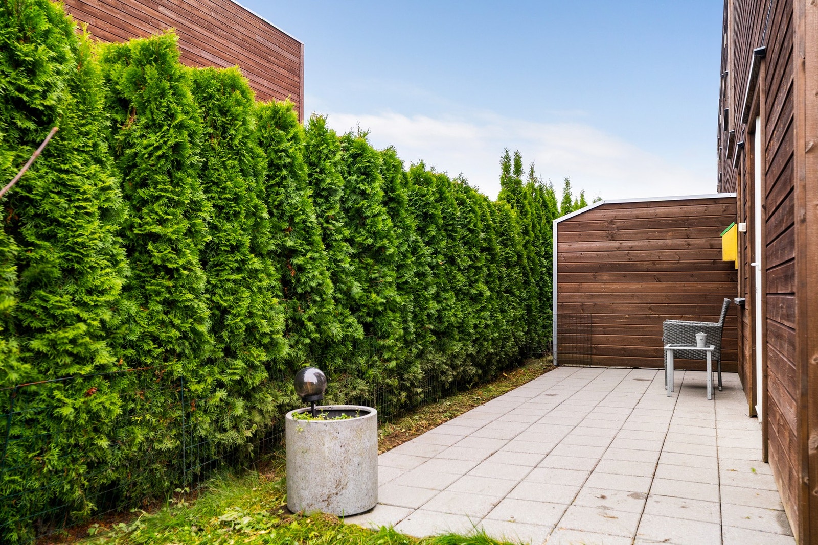 Uteplass på boligens bakside som ligger skjermet til med hekk og levegg. Galleribilde