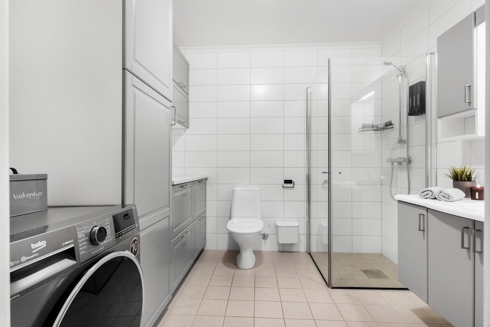 Flislagt bad i 1.etg. som er innredet med dusjnisje med glassvegger, toalett, baderomsinnredning med servant og speil, samt opplegg for vaskemaskin. Galleribilde