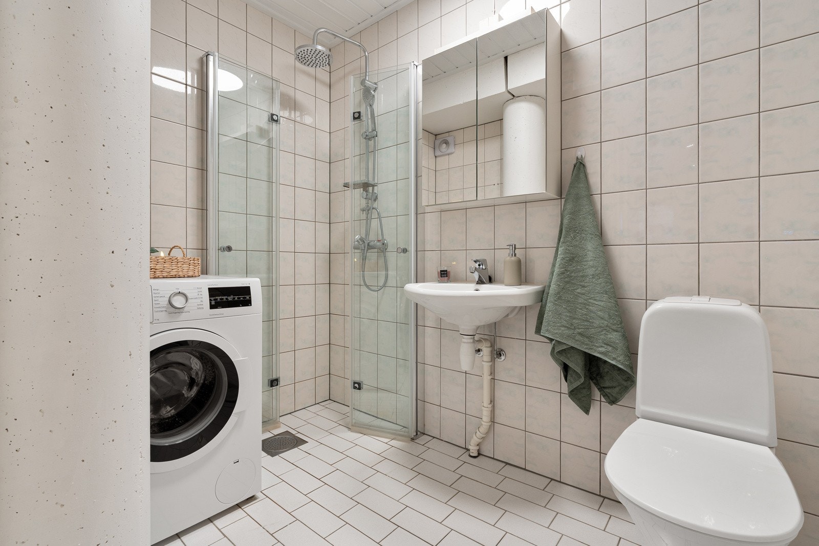 Flislagt bad med varmekalber. Speilskap med lagring til baderomsartikler.