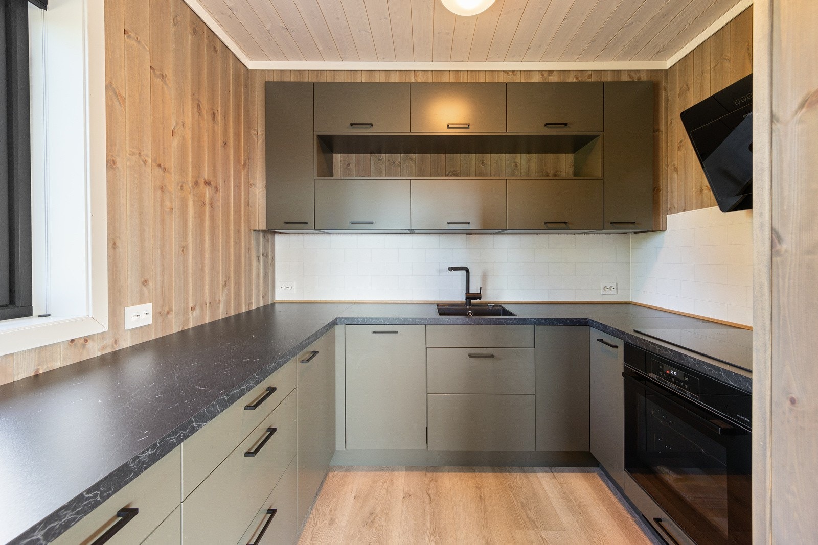 Kjøkkenet utstråler en moderne og ren estetikk med sine glatte fronter og laminatbenkeplate som strekker seg over 5,4 meter. Galleribilde