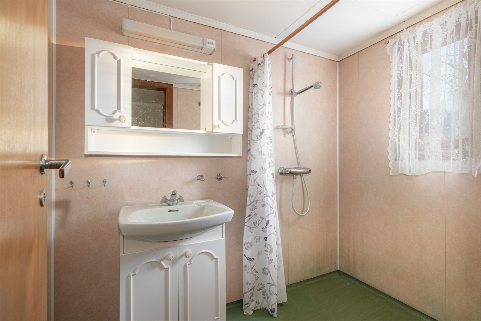 Badet innehar dusj på vegg og servantmøbel med skap og speil. Galleribilde