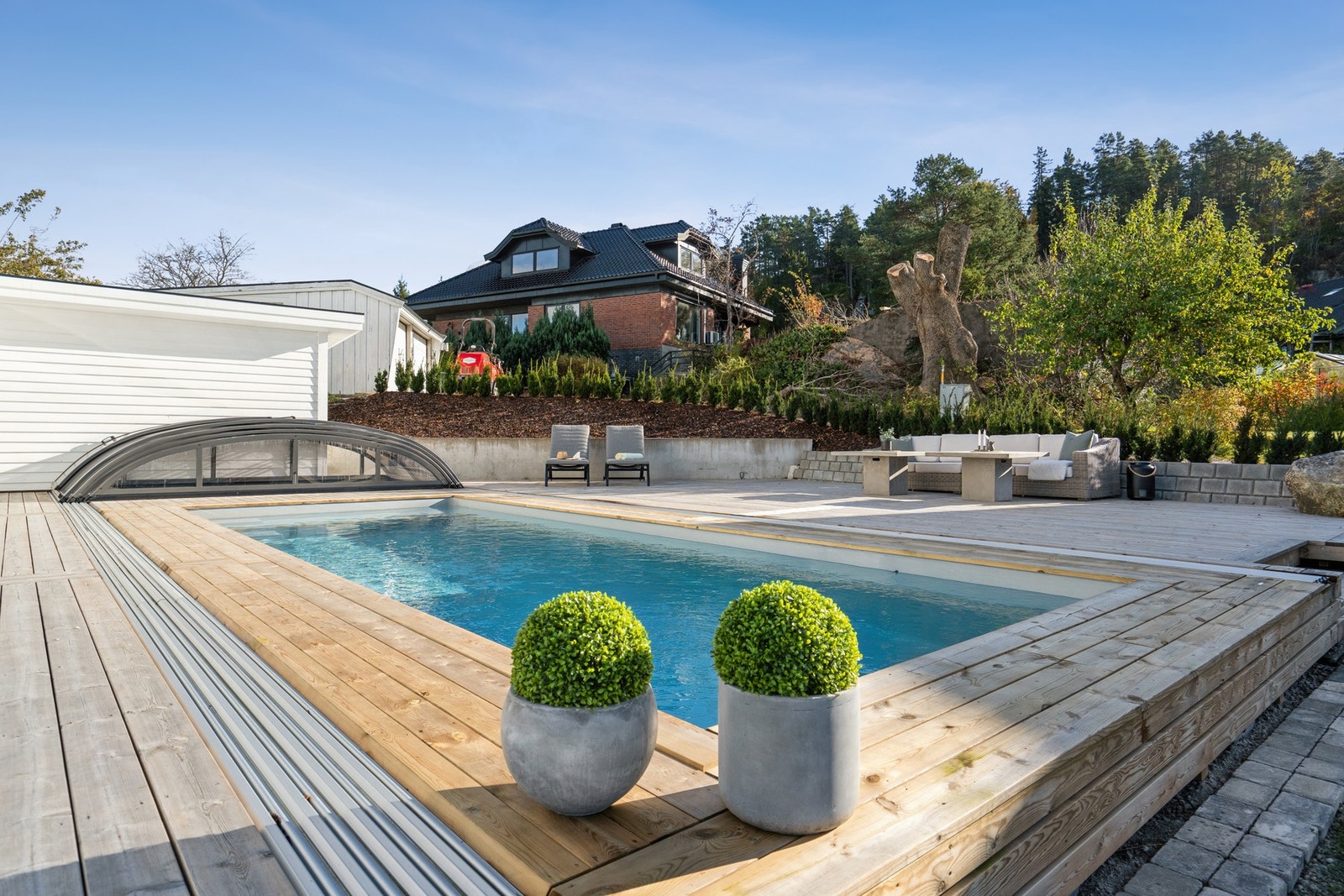 Store terrasser av tre med nedgravd svømmebasseng på 3,5 x 8 meter ligger på siden av boligen mot syd og vest. Galleribilde