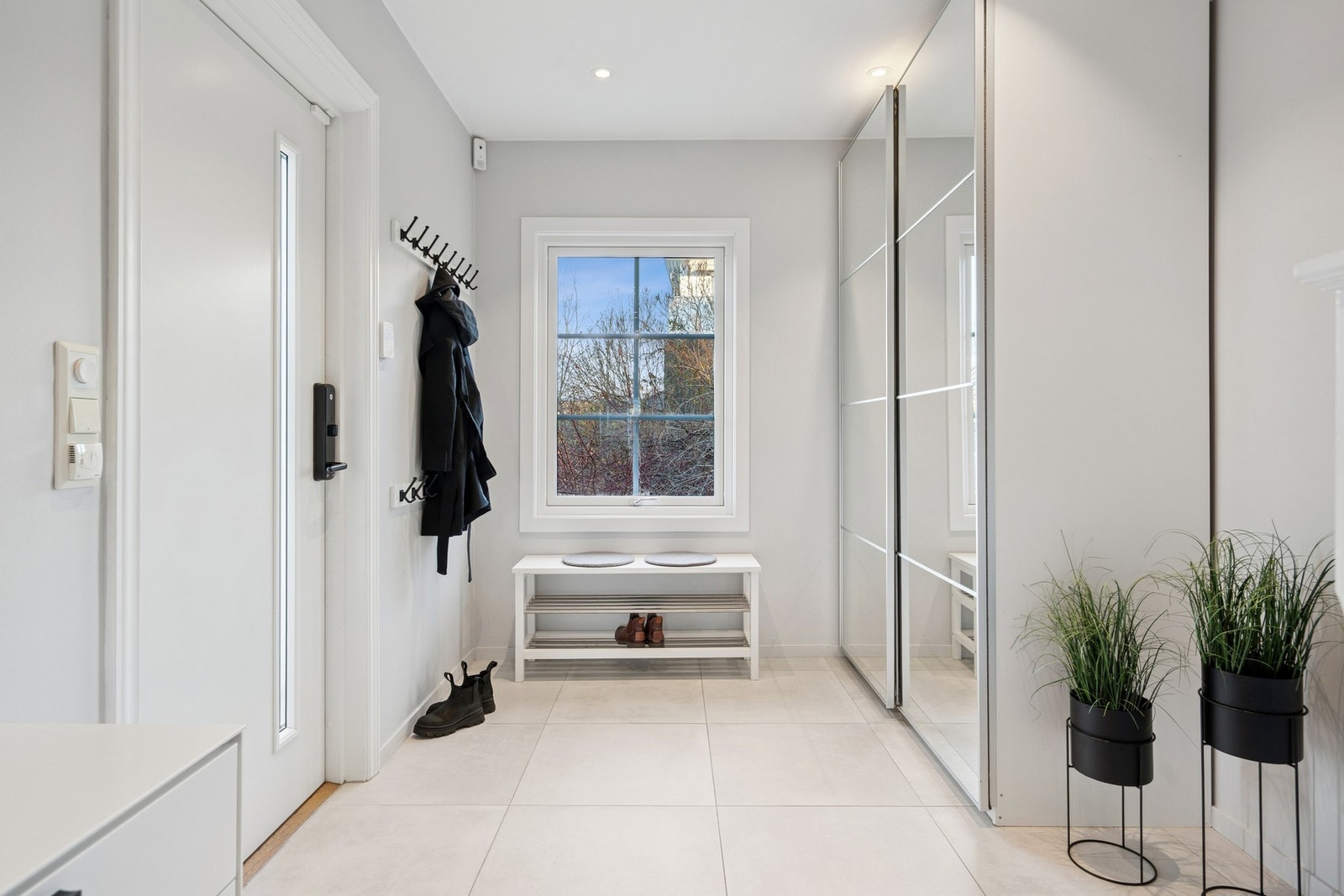 Lys og delikat entrè med skyvedørsgarderobe og downlights. Galleribilde