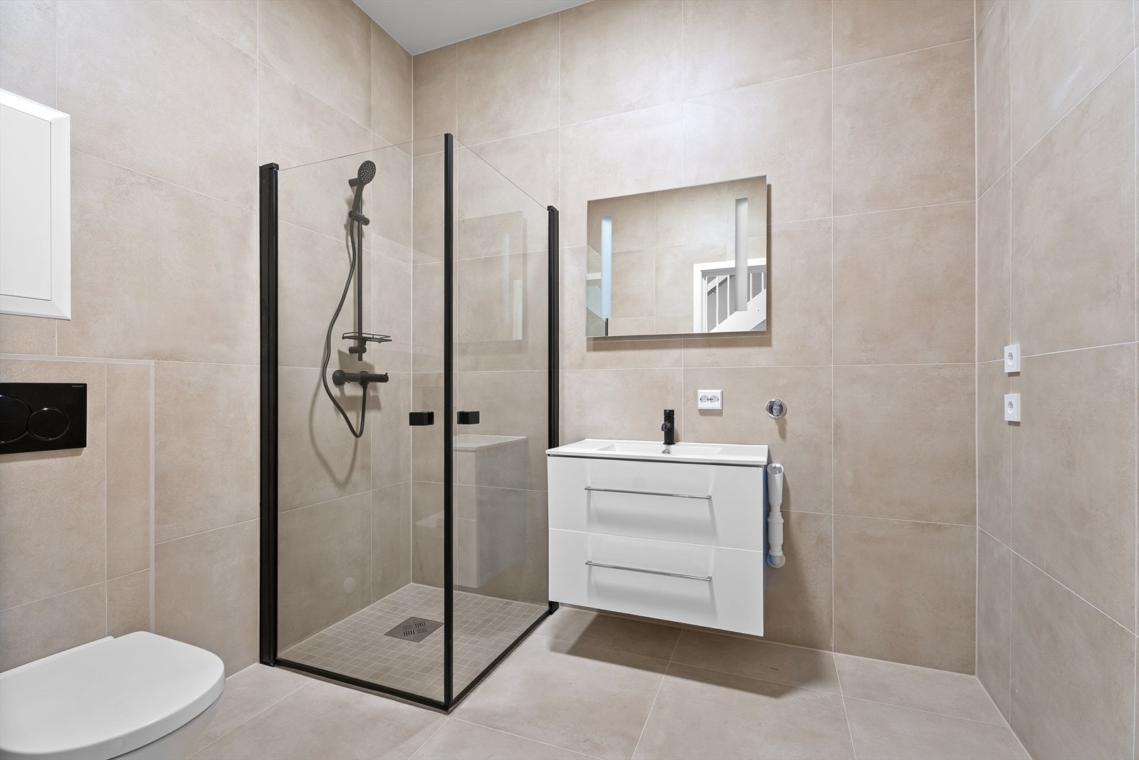 Flott flislagt bad med vegghengt toalett, dusjhjørne og innredning. Klargjort for vaskemaskin og tørketrommel. Galleribilde