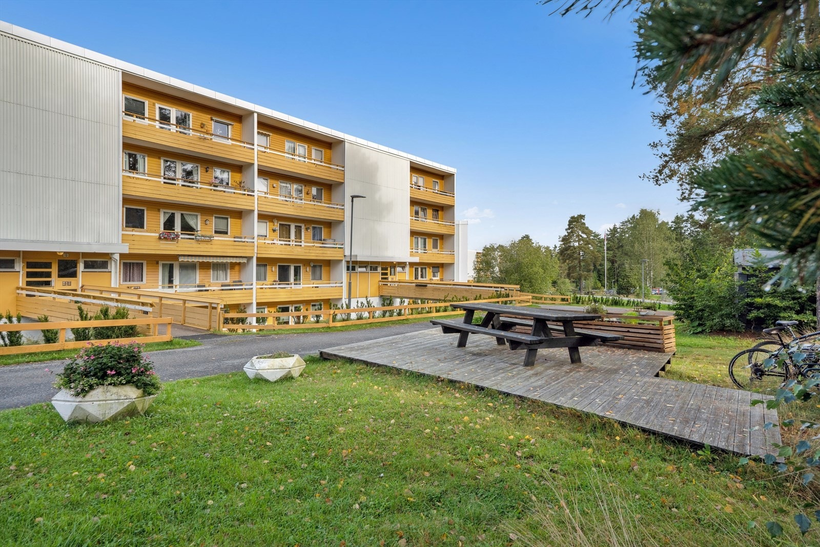 Grønne og frodige omgivelser rundt bygningene med plen og beplantning lett tilgjengelig for beboerne. Galleribilde