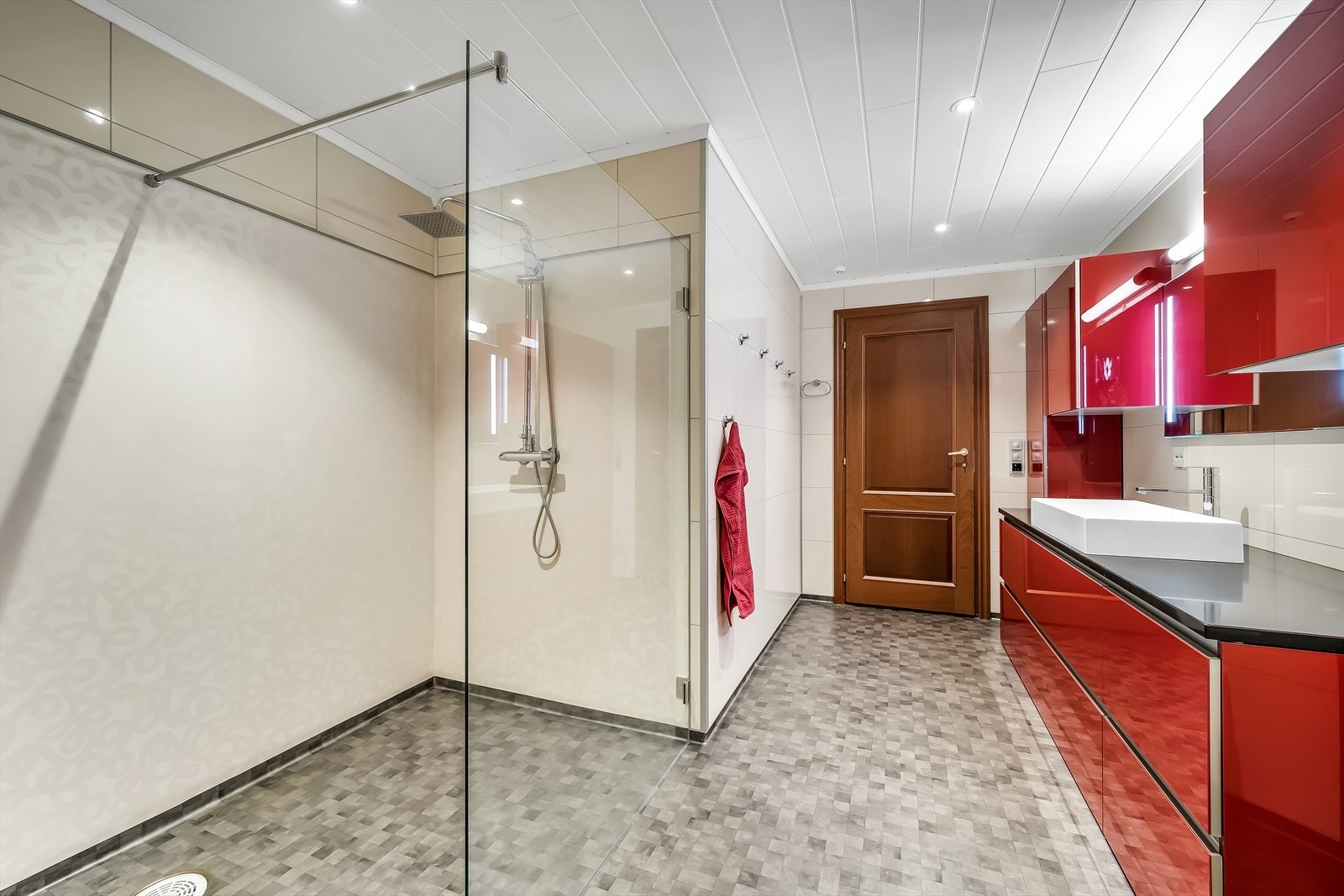 Badet har belegg på gulvet og baderomsplater på veggene, og er innredet med toalett, dusjhjørne og italiensk baderomsinnredning. Benkeplate i stein. Galleribilde