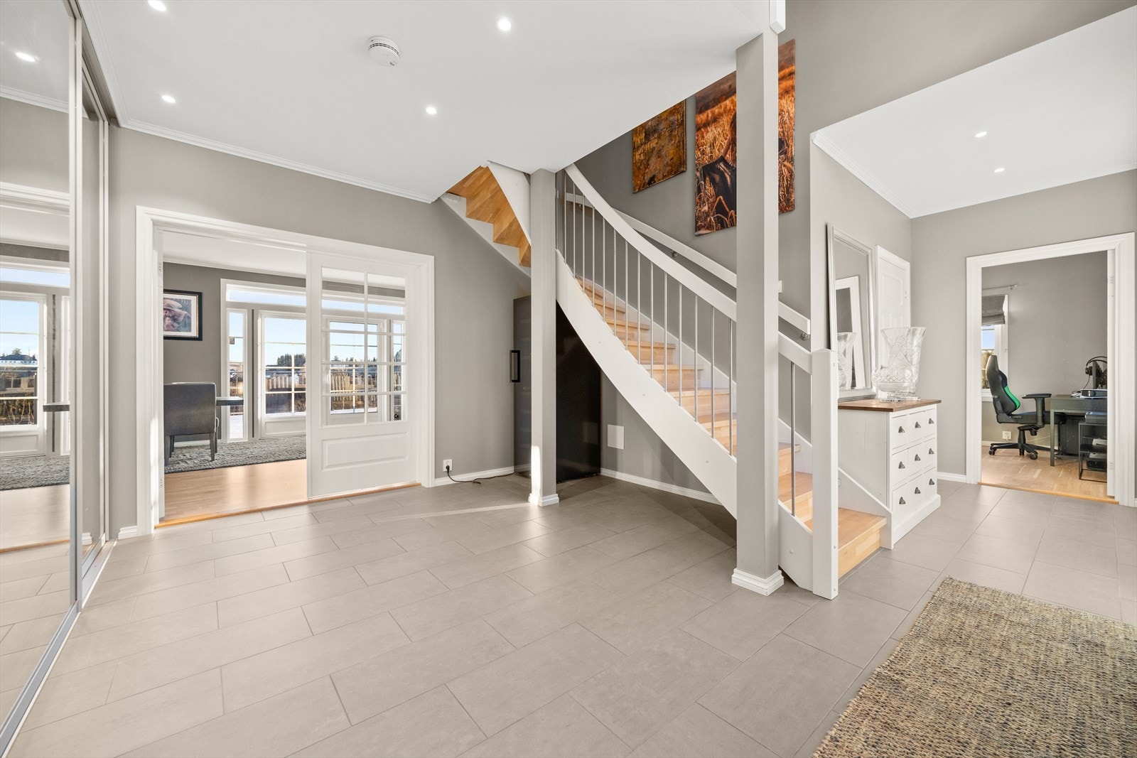 Stor hall med flislagt gulv med varmekabler, lyse vegger og downlights i himlingen. Galleribilde