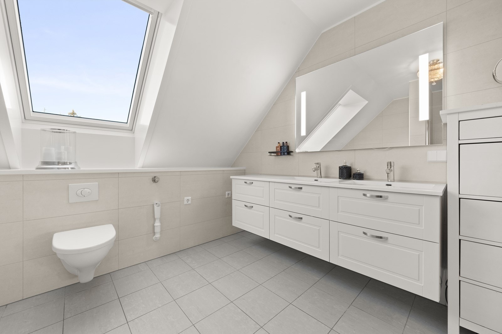 Stort hovedbad i andre etasje med dobbel servant, regnfallsdusj, vegghengt toalett og et frittstående badekar. Galleribilde