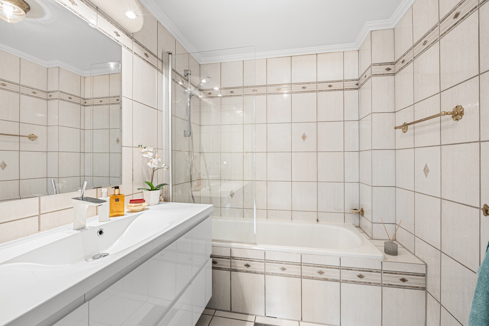 Badet i første etasje er eldre med flislagte overflater, innfliset badekar med dusj, lys servantinnredning og toalett. Galleribilde