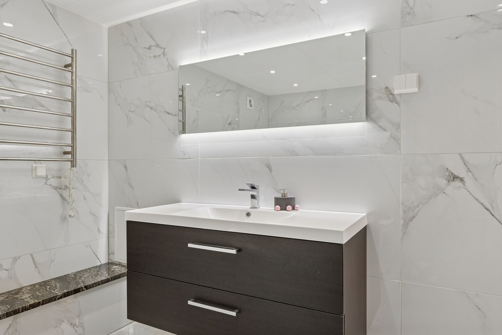 Badeommet er utstyrt med servantinnredning, håndkletørker, vegghengt toalett og badekar. Galleribilde