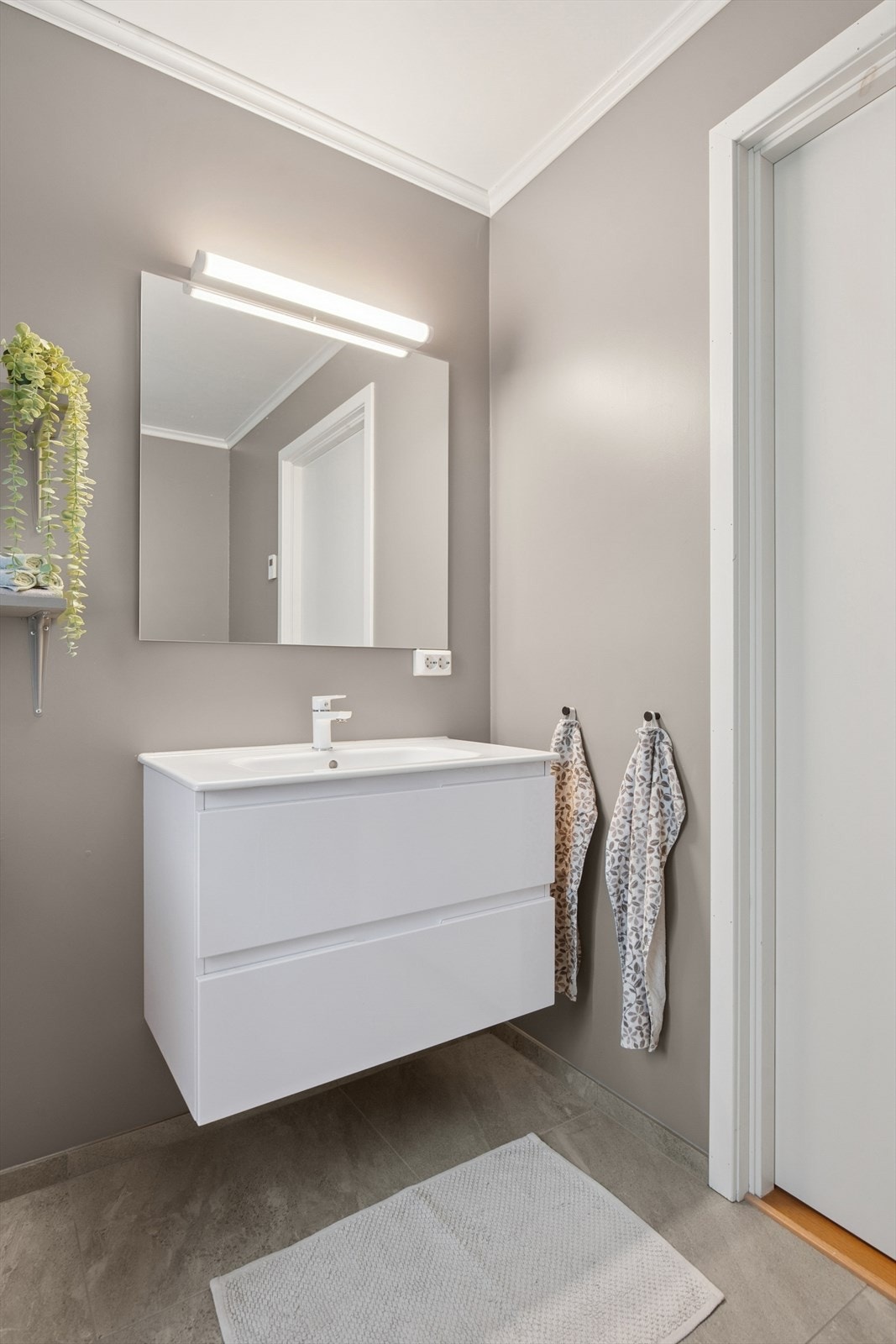 Baderom med servant, vegghengt toalett, dusj og opplegg for vaskemaskin. Galleribilde