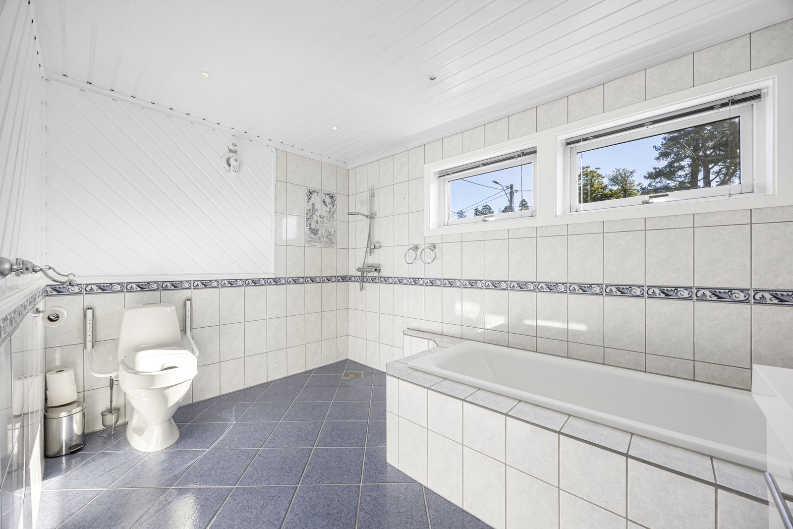 Hovedbadet er stort med fliser til tak og har dusjhjørne, badekar, opplegg for vaskemaskin, bred servantinnredning og varmekabler i gulv. Galleribilde