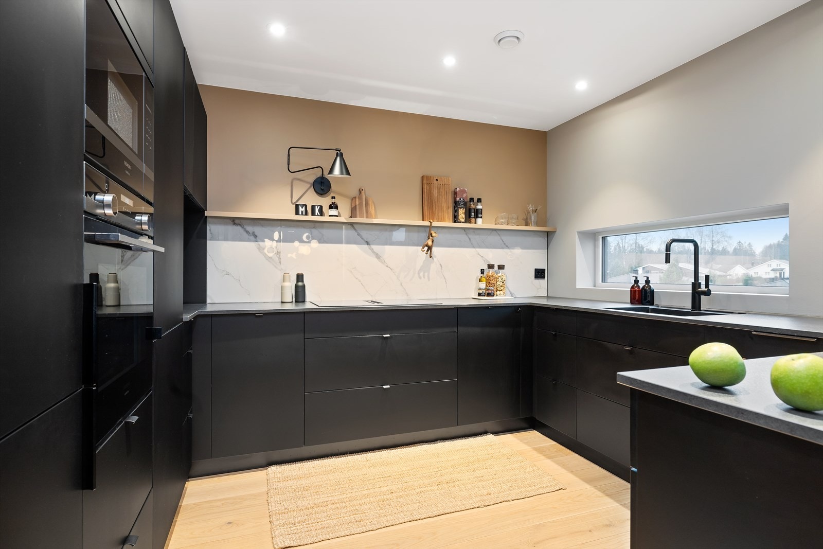 Kjøkken i åpen løsning med stue og spisestue og med mye skap- og benkeplass. Galleribilde