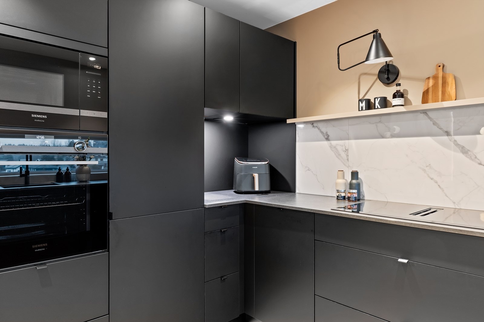 Den moderne innredningen består av svarte, slette fronter, laminat benkeplate og frittstående hylle. Galleribilde