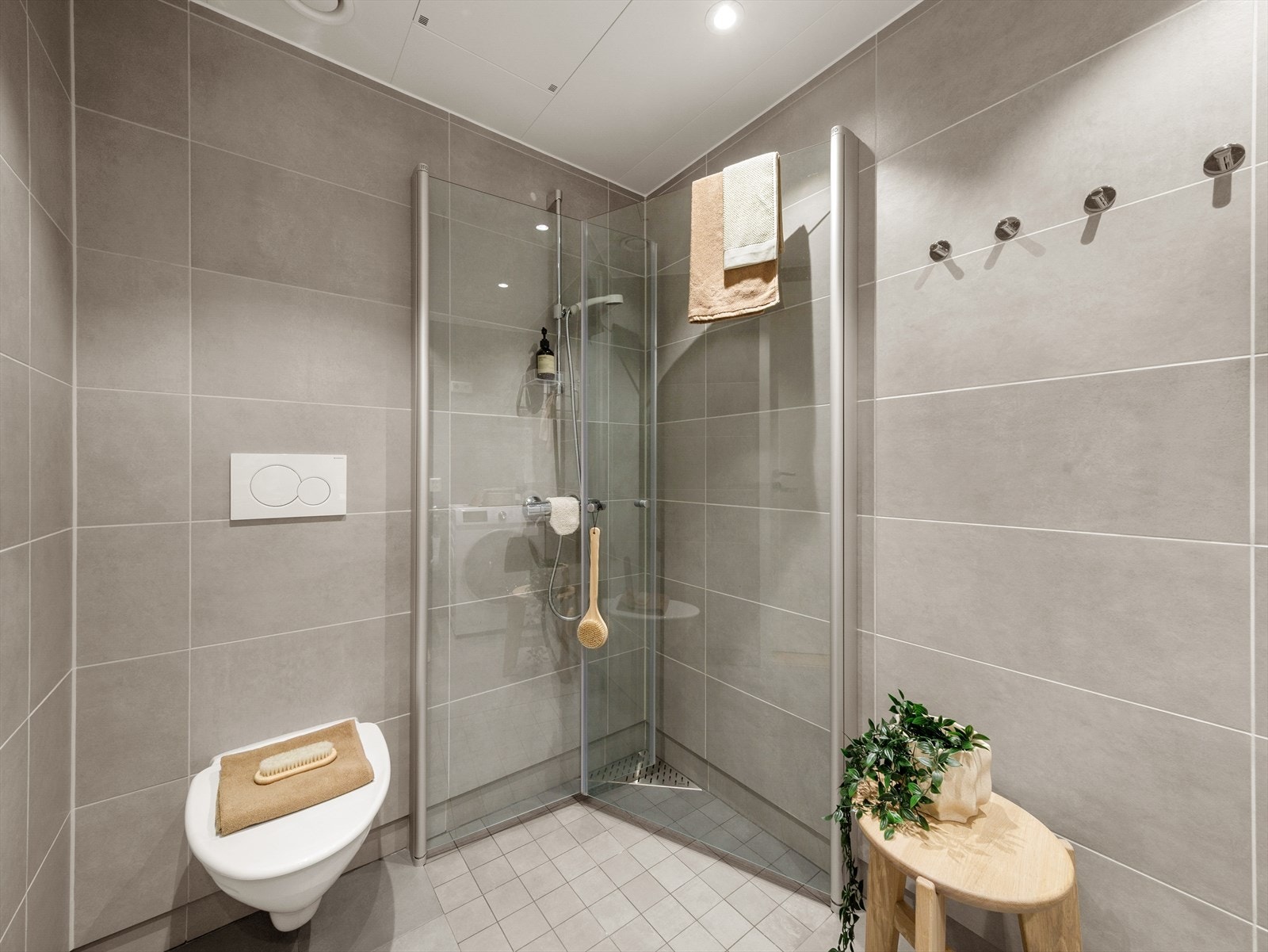 Pent helfliset bad innredet med baderomsinnredning med servant, vegghengt toalett, dusj og opplegg for vaskemaskin. Galleribilde