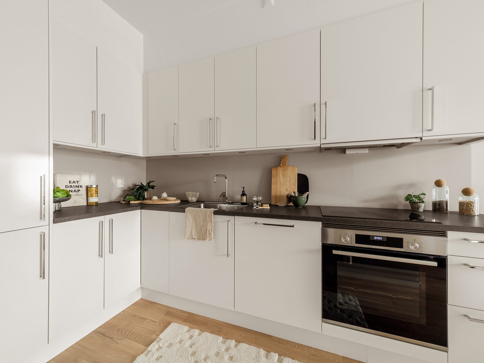 Kjøkkeninredning med slette, lyse fronter og benkeplate av laminat. Godt med skap- og benkeplass. Galleribilde