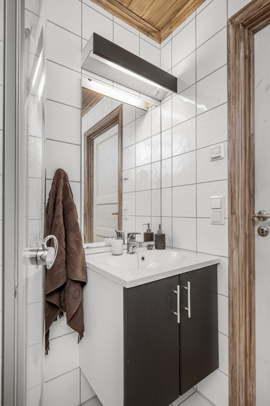 Innredningen består av servant med underskap, speil med belysning og dusjvegger. Gulvmontert wc og opplegg for vaskemaskin gir god funksjonalitet. Galleribilde