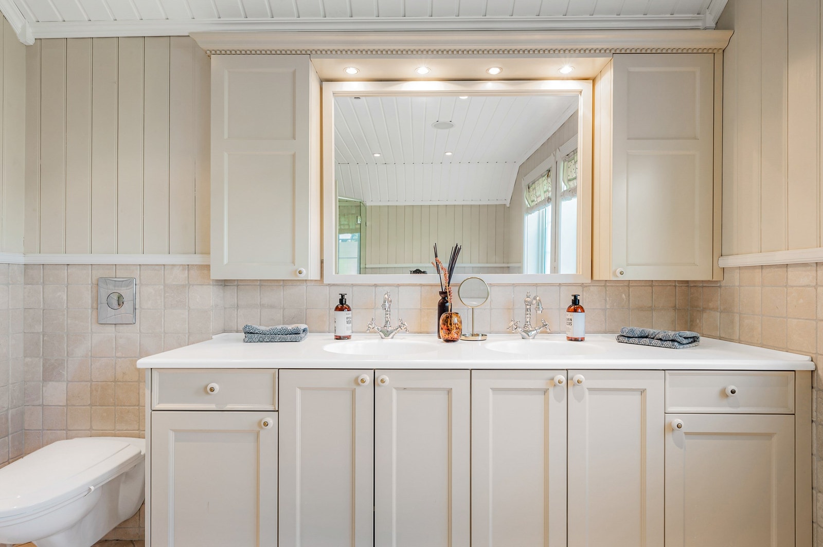 Stor innredning med profilerte fronter og heldekkende servant. Speilskap med integrert belysning. Galleribilde