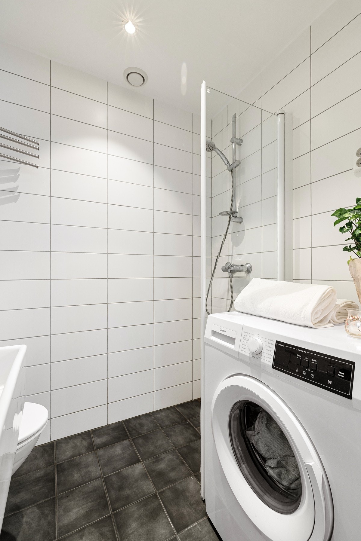 Badet er innredet med vegghengt toalett, dusjhjørne og servantseksjon med skuffer og speil. Galleribilde