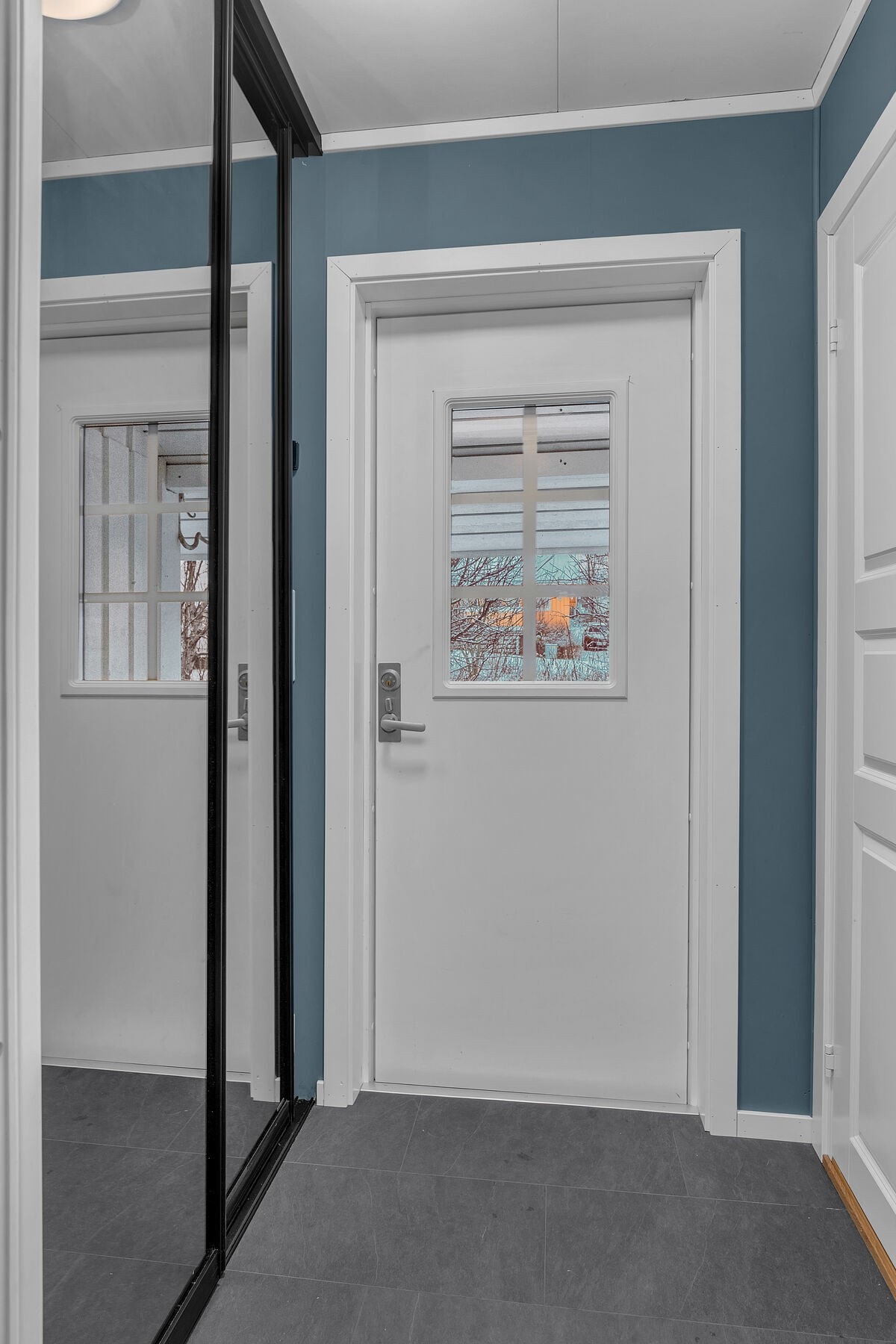 Vindfang med flislagt gulv, og som er praktisk innredet med skyvedørsgarderobe med speildører. Inn døren til høyre er det en bod. Galleribilde