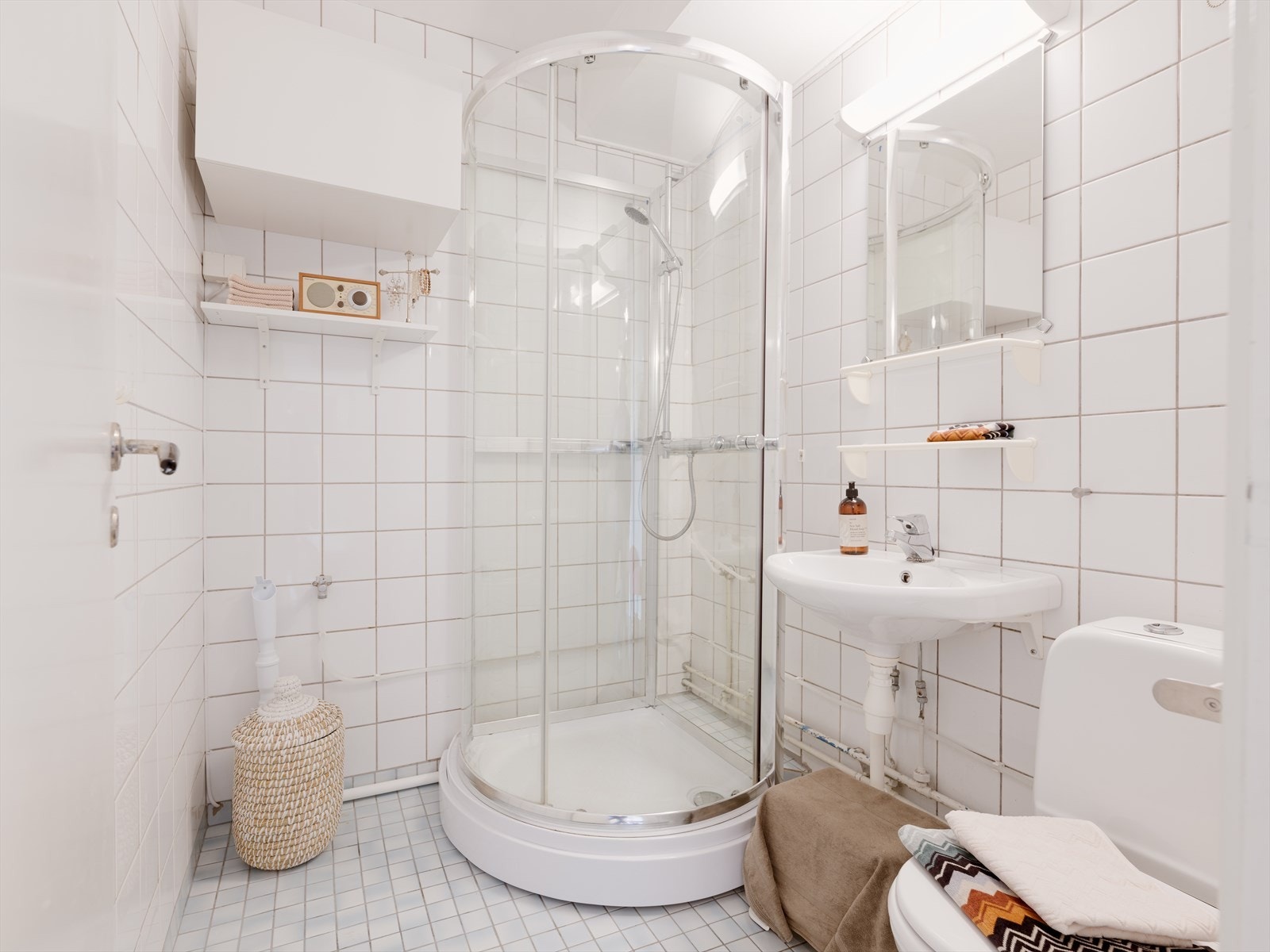 Flislagt bad innredet med klosett, servant med speil, dusjkabinett og vegghengt skap. Her er det opplegg for vaskemaskin, men vaskekjeller kan også benyttes. Galleribilde