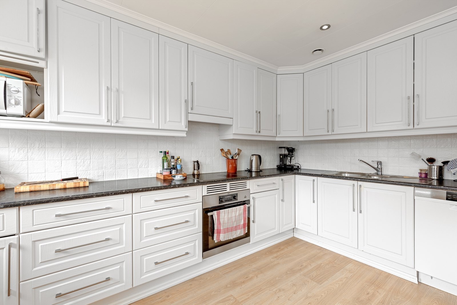 Integrerte kvitevarer som steikeovn og koketopp. Frittståande kjøl/frys, oppvaskmaskin og microovn. Galleribilde