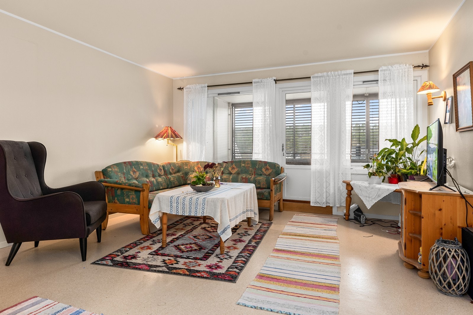 Lys stue, med belegg på gulvet og malt glassfiberstrie på veggene. Det er plass til salong, med tilhørende bord og interiør, samt TV Galleribilde