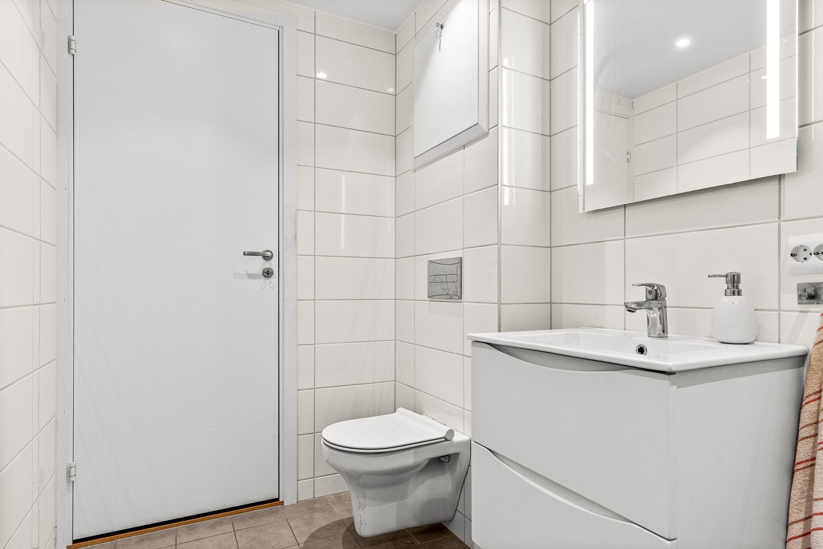 Baderommet ble pusset opp i regi av borettslaget i 2022, og er klassisk flislagt på gulv og vegger. Det er innredet med stilren servantinnredning, med speil med ledbelysning over. I tillegg er det vegghengt wc Galleribilde