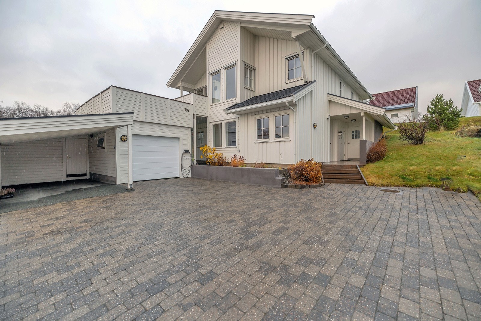 Innkjørselen er pent steinlagt. Parkering både i garasje og carport i tillegg til oppstillingsplasser Galleribilde