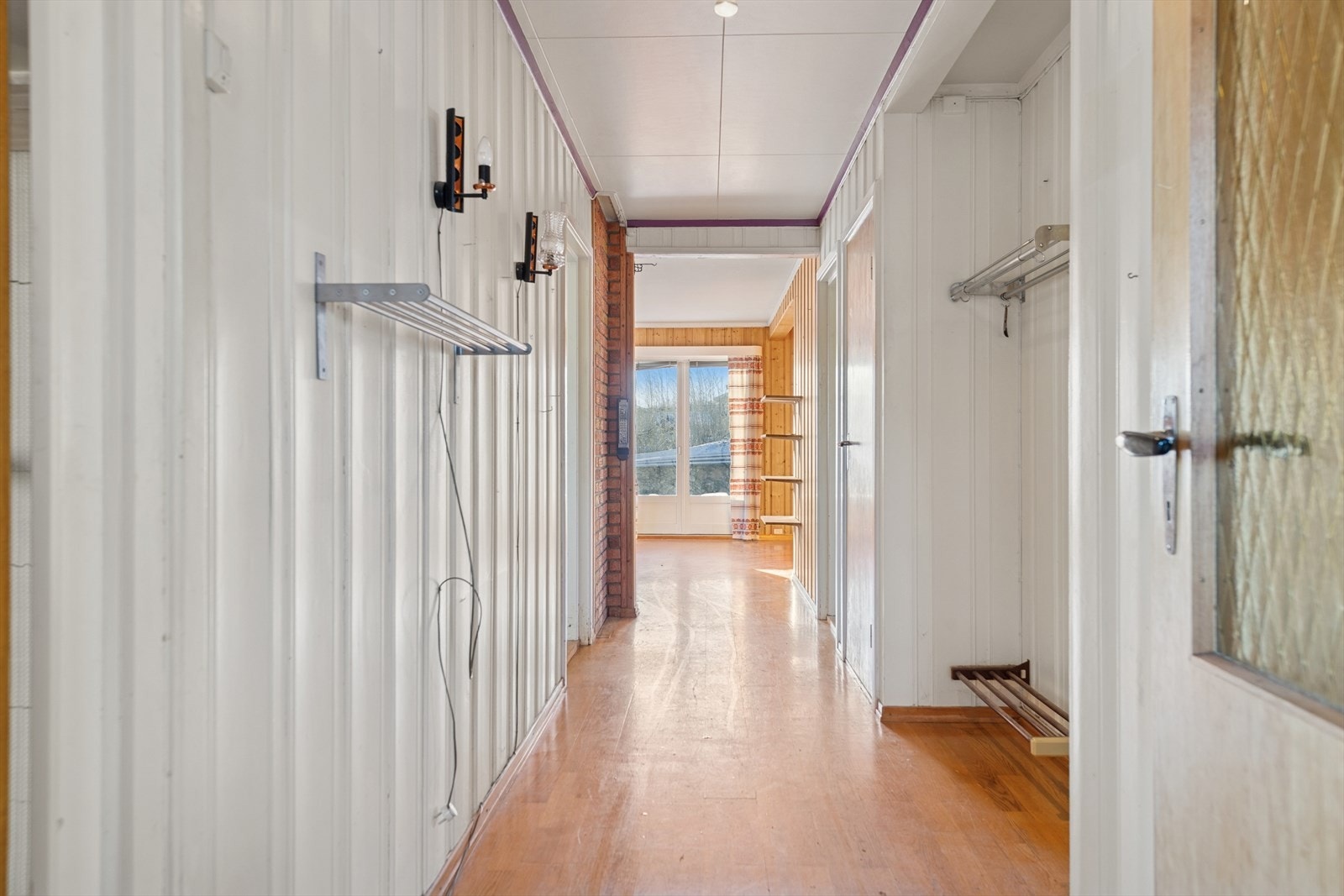 Panelvegger og tregulv preger entréen, med plass til oppbevaring langs veggen. Galleribilde