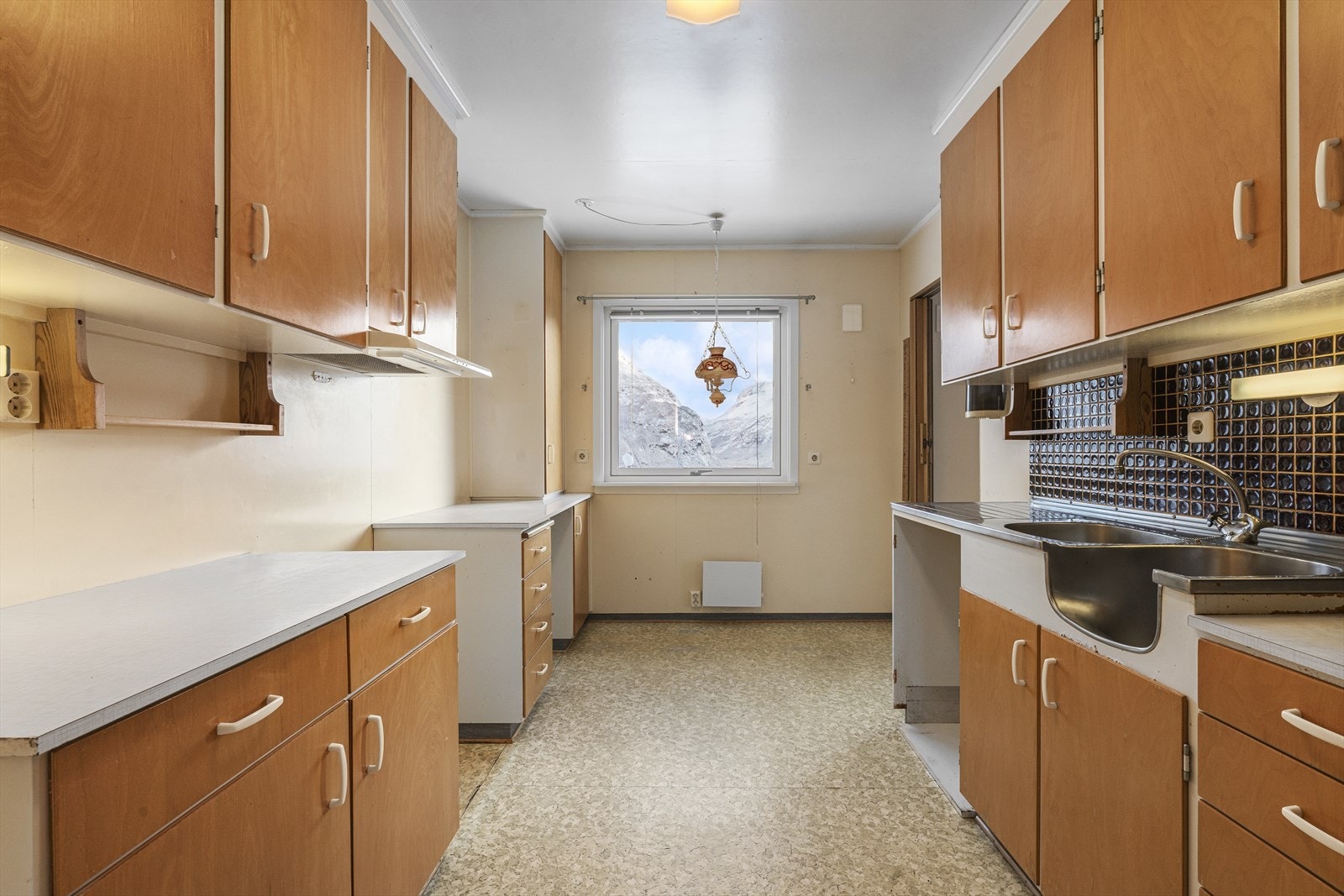 Kjøkkenet har original innredning fra byggeår. Ved vinduet er en ypperlig plass for et lite kjøkkenbord, hvor man kan nyte morgenkaffen og utsikten samtidig. Galleribilde