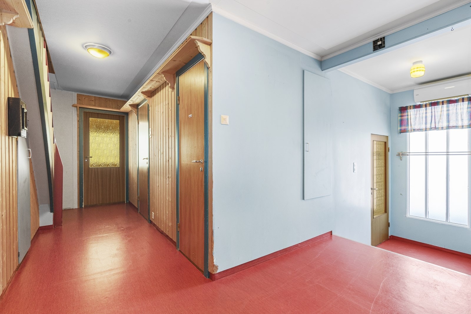 Gangen ved entrè har rødt gulvbelegg og malte, slette vegger. Galleribilde