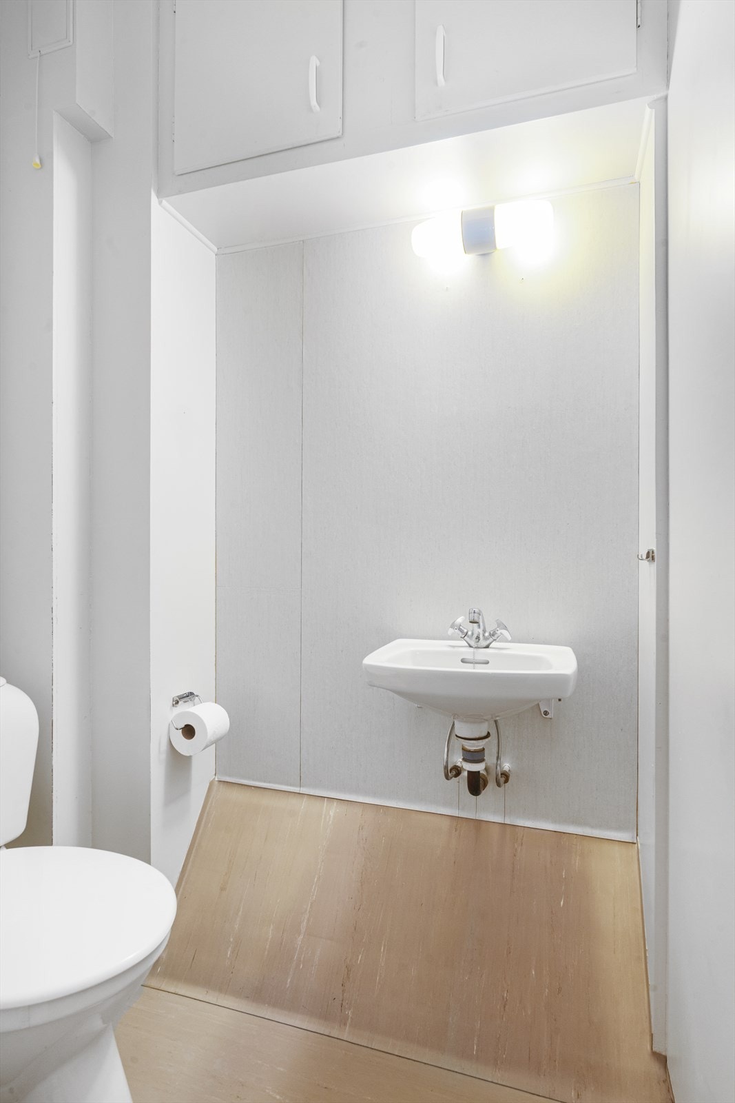 Toalettrommet er utstyrt med wc, en liten servant og innebygde skap over vasken. Galleribilde