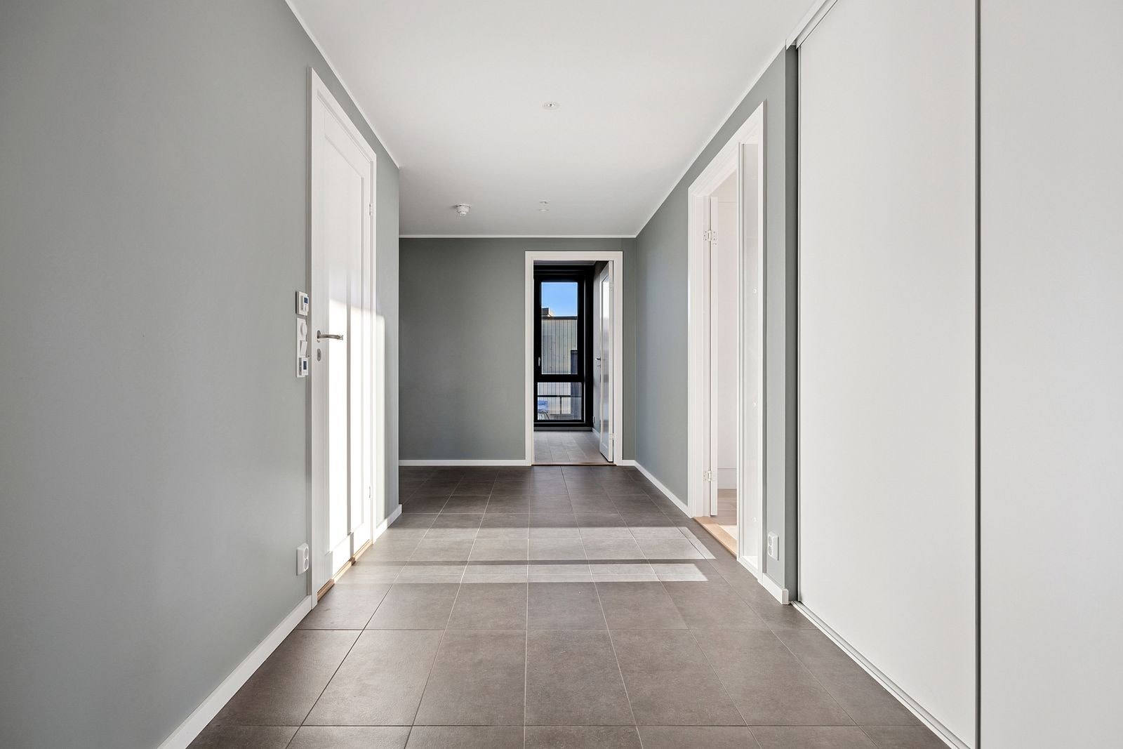 Flislagt entrè med praktisk skyvedørsgarderobe. Galleribilde