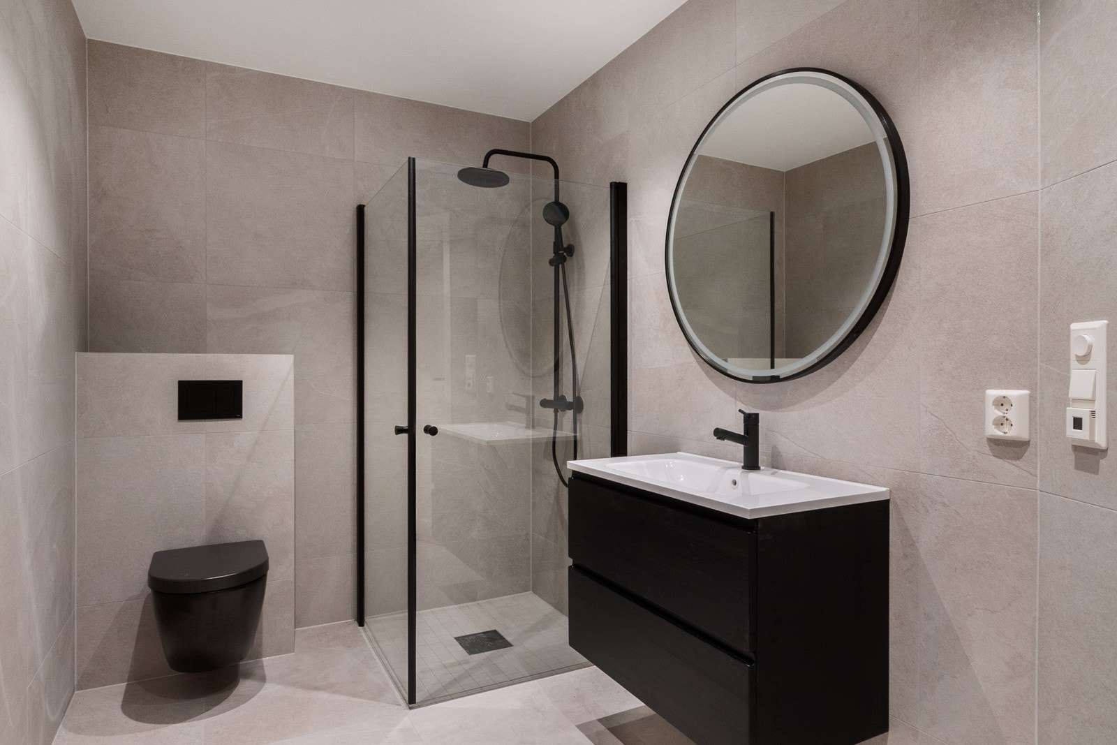 Gjennomført bad med moderne materialvalg og flislagte overflater Galleribilde