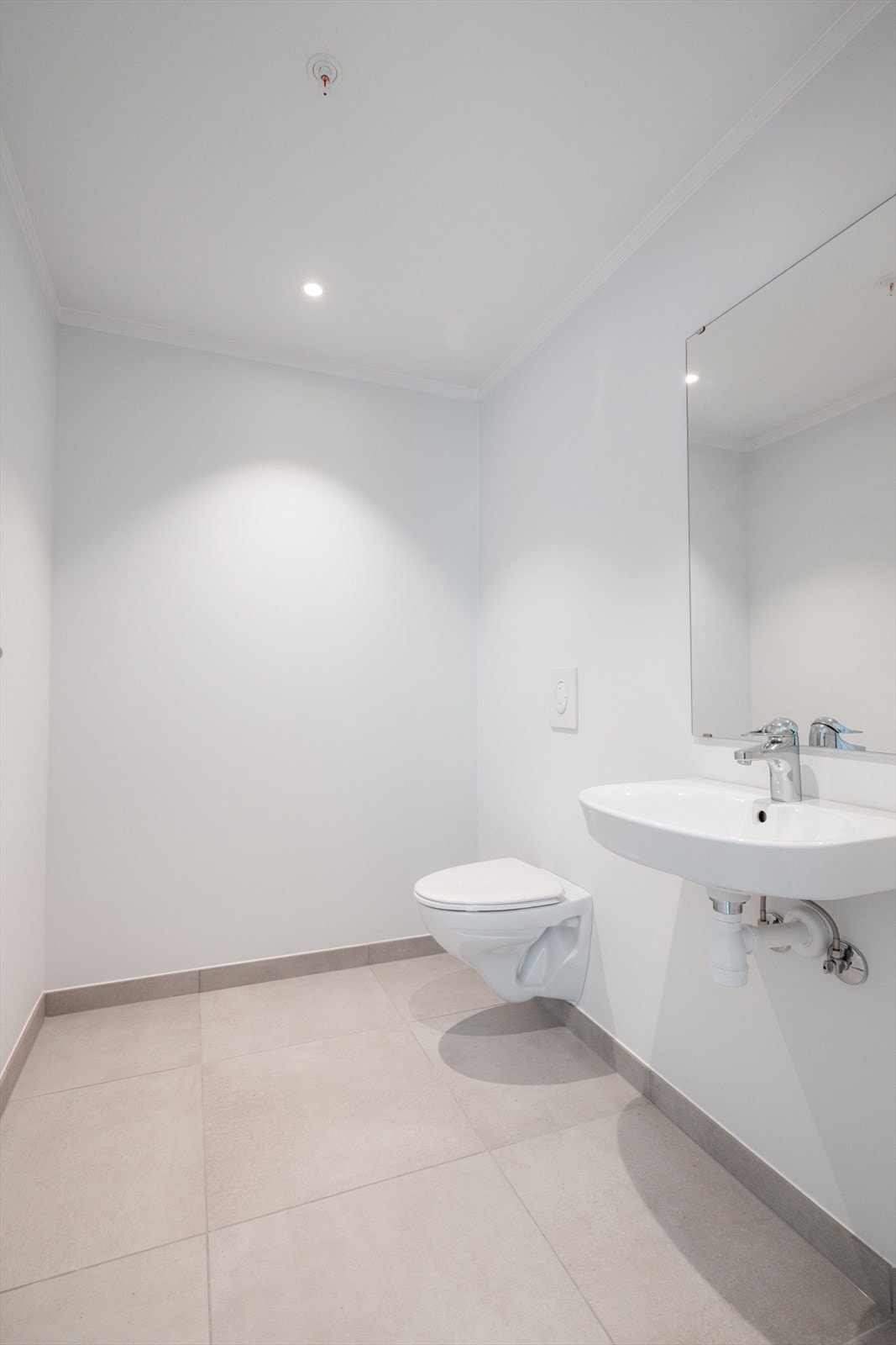 Toalettrommet har veggmontert toalett og servant på vegg. Galleribilde