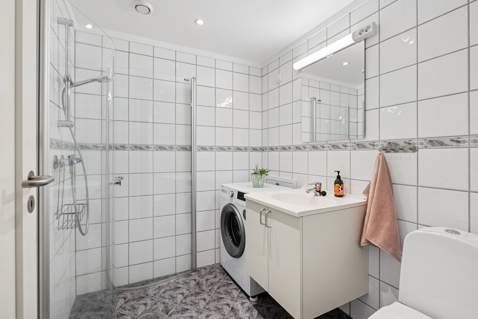 Badet er innredet med servant i servantskap, gulvmontert toalett og dusjhjørne med vegger i herdet glass. Galleribilde