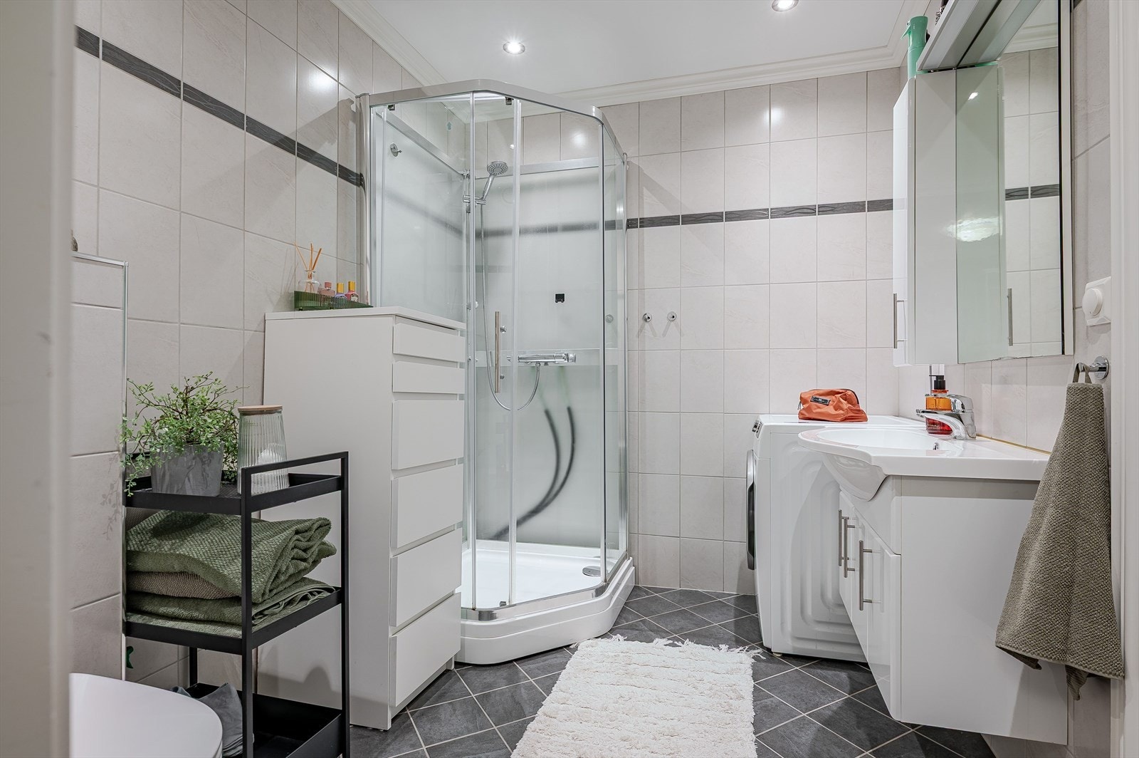 Lyst og moderne baderom fra 2015 med fliser på gulv og vegger, elektriske varmekabler, downlights i himlingen, balansert ventilasjon og opplegg for vaskemaskin. Galleribilde