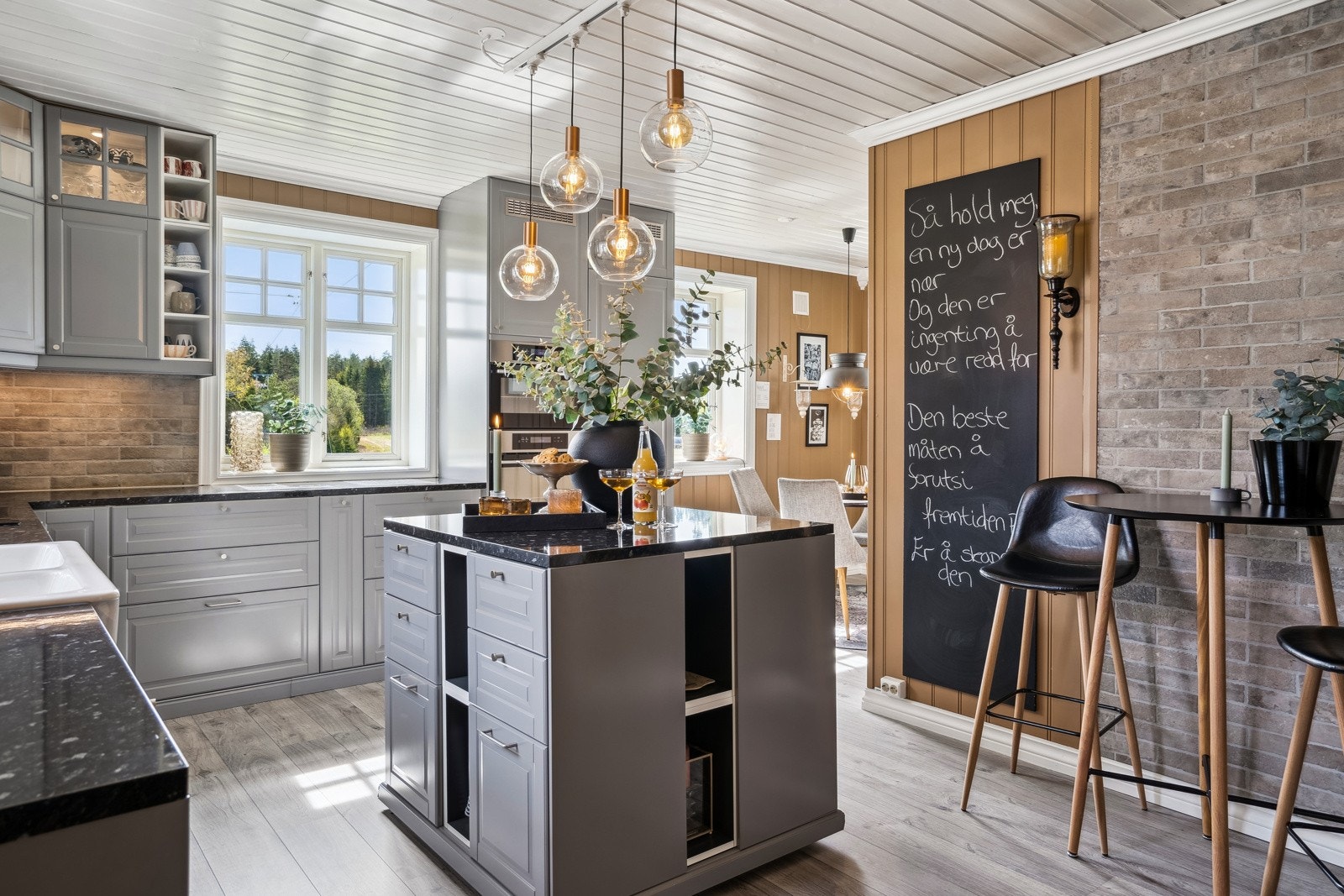 Praktisk kjøkken, kjøkkenøy på hjul, vitrineskap med belysning og fliser over benk. Galleribilde