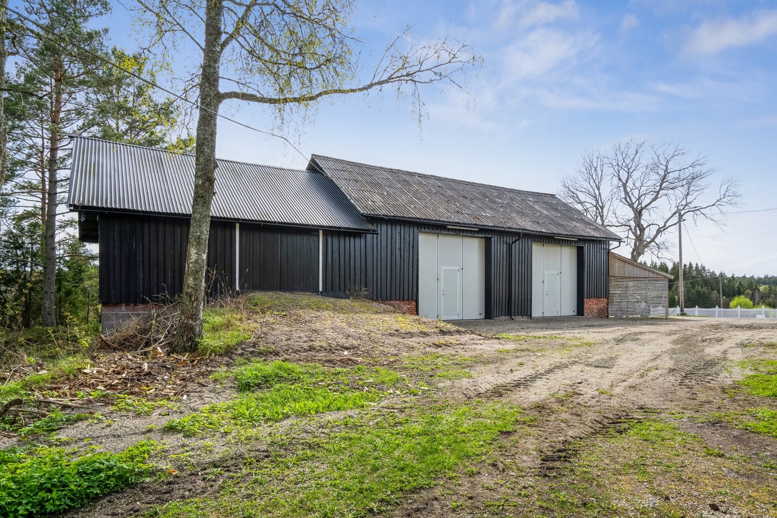 Et velholdt vognskjul fra 1980 ble tilbygd med en trippel carport i 2020 og malt opp i 2024. Galleribilde